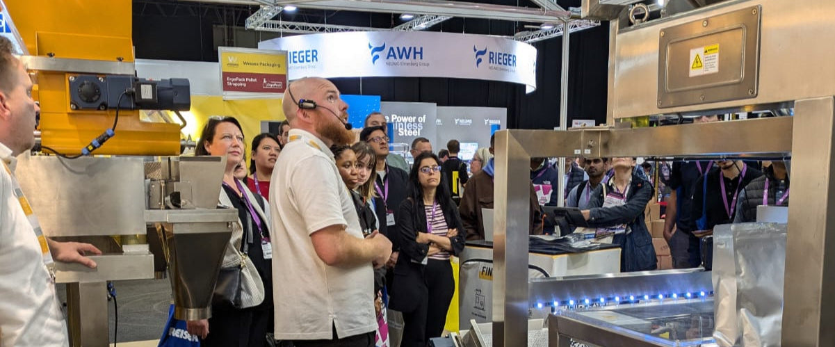 People at a trade show or exhibition with industrial equipment and booths.